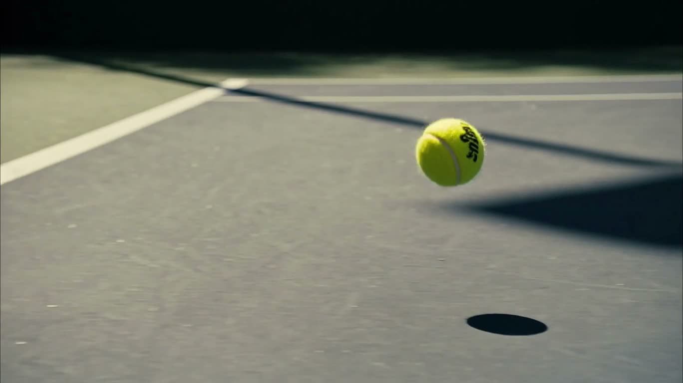 Quả bóng tennis nảy trên sân ngập nắng